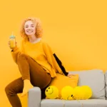 אשה שותה מיץ תפוזים נשענת על ספה בלוני סמיילי לידה