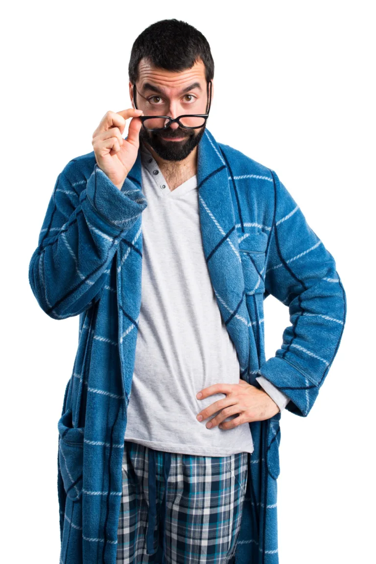 גבר מזוקן לבוש חלוק משובץ כחול מטה את המשקפיים במבט תוהה